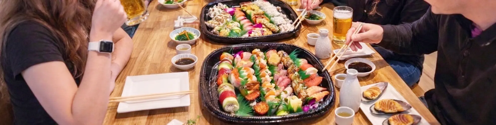 People dining together with large sushi platters and drinks